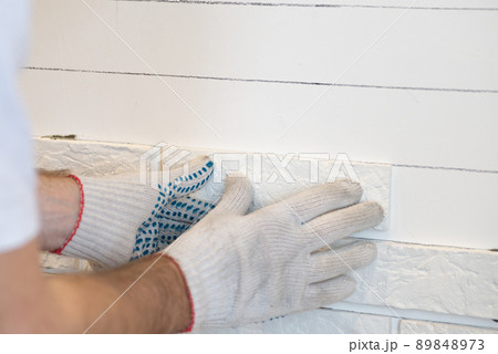 Professional Builder gluing decorative tile on wall. worker mounts decorative brick on wall 89848973