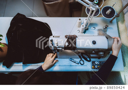 A woman tailor sews clothes - a fashionable jacket made of velvet fabric on a sewing machine in her atelier 89850424