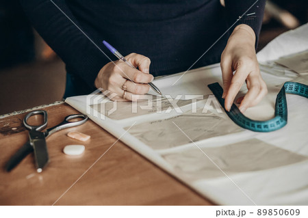 Tailor sews clothes. A woman dressmaker makes patterns in her atelier 89850609
