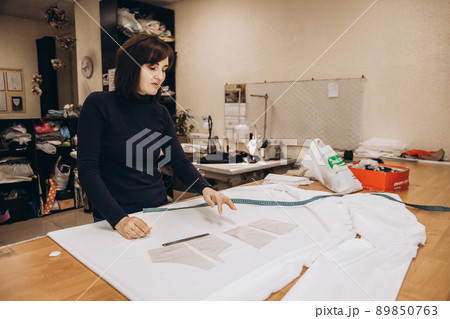 The tailor lays out the patterns on the fabric and begins to sew clothes 89850763