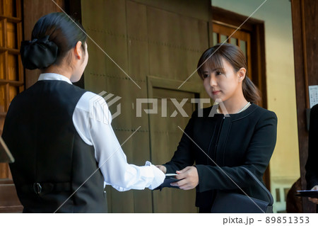 葬式で香典を渡す喪服を着た弔問客 89851353