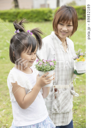 花をじっくりと観察しガーデニングを楽しんでいる女性と子供 花をじっくりと観察しガーデニングを楽しんでいる女性と子供 89852189