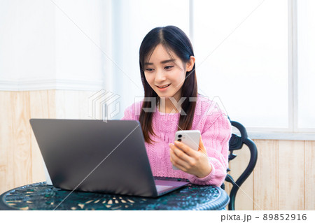 パソコンで調べながら慎重にアプリでネットショッピングをする若い女性 89852916