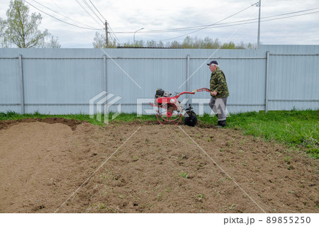 The farmer cultivates the field with a walk-behind tractor. The farmer cultivates the field with a walk-behind tractor. 89855250