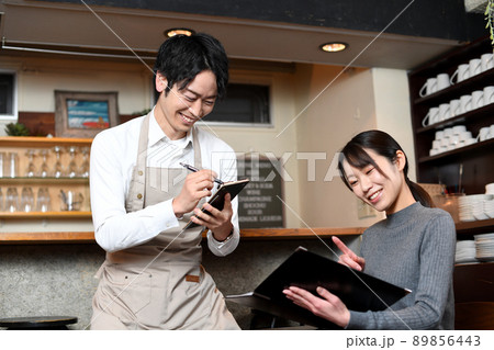 飲食店で働くエプロン姿の男性と女性客 飲食店で働くエプロン姿の男性と女性客 89856443