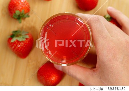 Fresh delicious strawberry juice pours into a glass. Healthy antioxidant juice with vitamin from ripe fruits. Top view. Selective focus 89858182
