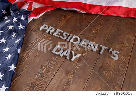 words presitdents day laid with silver letters on wooden surface near US flag 89860016