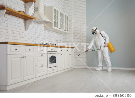 Pest control worker spraying chemical to get rid of rodents, termites or cockroaches in the house 89860500