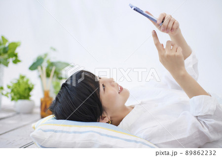 リビングでスマホを見る若い女性 89862232