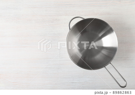 Metal bowl on white wooden background, space for text 89862863