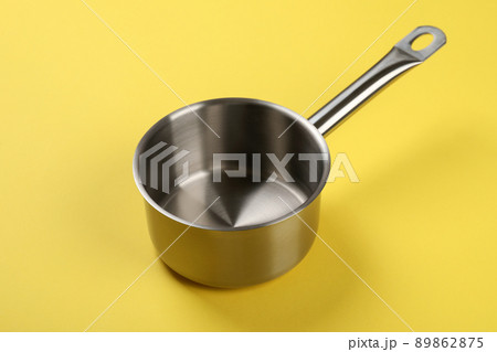 Metal empty bowl on yellow background, close up Metal empty bowl on yellow background, close up 89862875