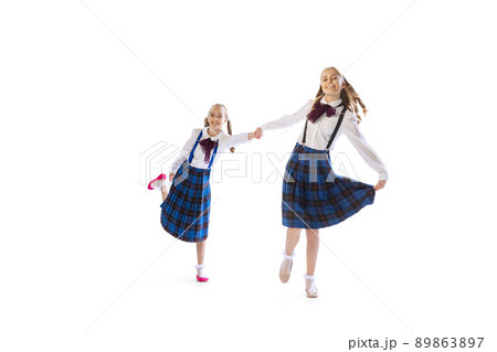 Portrait of little girls, twins having fun together, posing isolated over white studio background Portrait of little girls, twins having fun together, posing isolated over white studio background 89863897