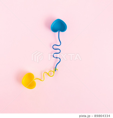 Pastel colored plastic dishes and drinking straws placed like clock hands on a pink background. 89864334