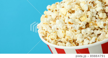 Paper cup with popcorn on blue background Paper cup with popcorn on blue background 89864791