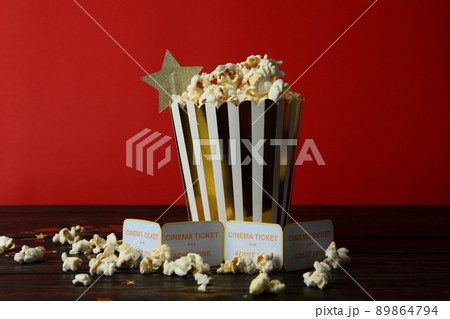 Paper box with popcorn, and tickets against red background Paper box with popcorn, and tickets against red background 89864794