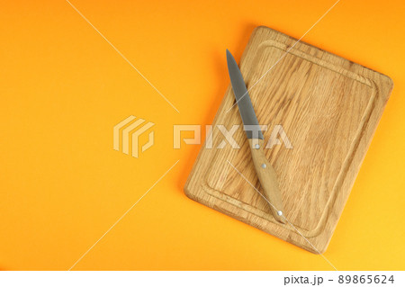 Cutting board with knife on orange background 89865624