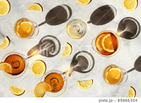 Summer cocktails in the sunlight. Fresh juicy beverages in glasses with shadows making trendy pattern. Delicious lemonade, cold tea, soda and water on gray marble background Summer cocktails in the sunlight. Fresh juicy beverages in glasses with shadows making trendy pattern. Delicious lemonade, cold tea, soda and water on gray marble background 89866304