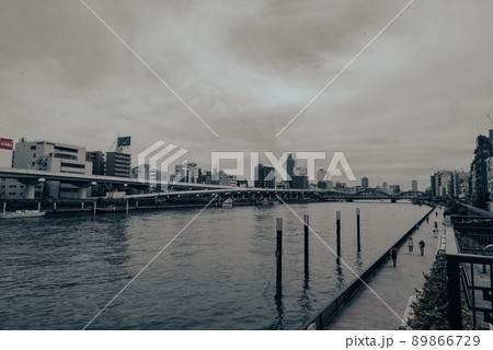 曇り空の下で川沿いを歩く人々 89866729
