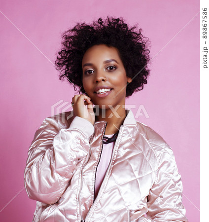 young pretty fashion styled african girl posing emotional cheerful on pink background, lifestyle people concept close up 89867586
