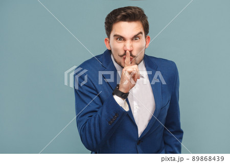 Man showing shh, silence sign. Business people concept, richly and success. Indoor, studio shot on light blue background Man showing shh, silence sign. Business people concept, richly and success. Indoor, studio shot on light blue background 89868439