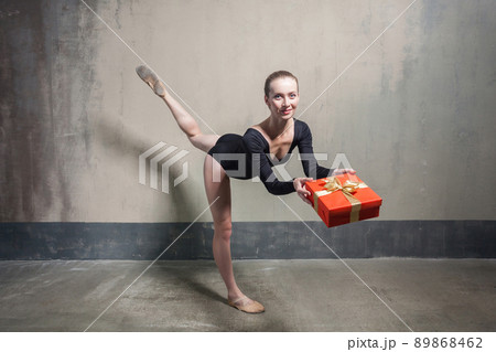 Beautiful ballerina balance in one leg and holding red gift box. Indoor 89868462