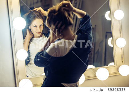Beautiful young adult freckles woman looking at her reflection in a dressing room mirror. Studio shot 89868533