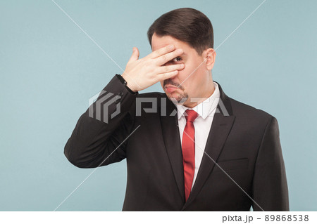 spy on, Curious through the fingers of curiosity. indoor studio shot. isolated on light blue background. handsome businessman with black suit, red tie and mustache looking at camera. spy on, Curious through the fingers of curiosity. indoor studio shot. isolated on light blue background. handsome businessman with black suit, red tie and mustache looking at camera. 89868538