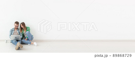 Planning summer vacation or online order. Cute young couple searching hotel and resort online using laptop on floor at home - white background banner with copy space and place for advertising 89868729