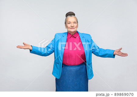 Welcome my dear! Happiness woman looking at camera. Emotion and feelings concept. Portrait of handsome expressive grandmother standing with collected gray hair. Studio shot isolated on gray background Welcome my dear! Happiness woman looking at camera. Emotion and feelings concept. Portrait of handsome expressive grandmother standing with collected gray hair. Studio shot isolated on gray background 89869070