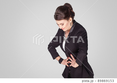Stomach pain, period. Woman have a pms. Studio shot, indoor. Isolated on grey background Stomach pain, period. Woman have a pms. Studio shot, indoor. Isolated on grey background 89869153