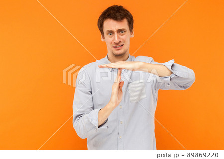 I need time out. Unhappy man showing stop sign at camera. Studio shot, orange background I need time out. Unhappy man showing stop sign at camera. Studio shot, orange background 89869220