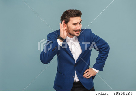 Don't hear you. Secret news. Business people concept, richly and success. Indoor, studio shot on light blue background Don't hear you. Secret news. Business people concept, richly and success. Indoor, studio shot on light blue background 89869239