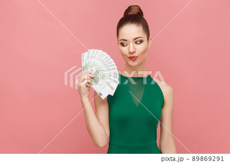 Woman looks with desire on money. Expression emotion and feelings concept. Studio shot, isolated on pink background 89869291