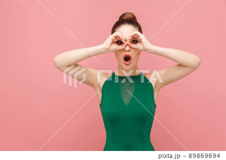Binoculars sign. Woman looking far far away. Expression emotion and feelings concept. Studio shot, isolated on pink background Binoculars sign. Woman looking far far away. Expression emotion and feelings concept. Studio shot, isolated on pink background 89869694