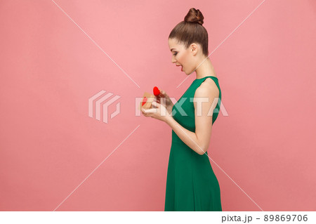 Profile photo of beautiful woman holding gift box with hearts. Expression emotion and feelings concept. Studio shot, isolated on pink background Profile photo of beautiful woman holding gift box with hearts. Expression emotion and feelings concept. Studio shot, isolated on pink background 89869706