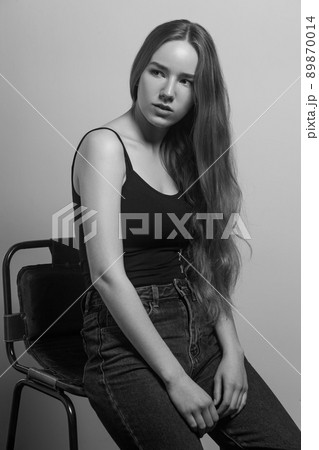 Beautiful woman sit on chair and looking away. Studio shot, isolated on gray background 89870014