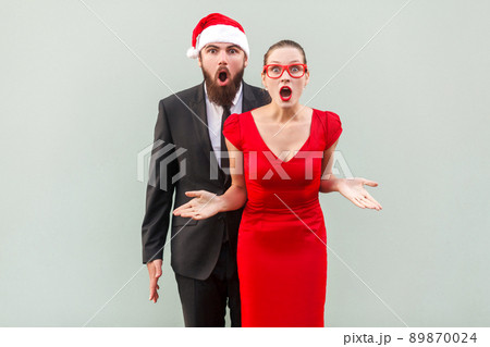 Businessman and woman looking at camera, standing together, open mouth with amazed face. Studio shot, gray background 89870024