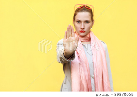 Negative human emotions, body language. Isolated studio shot. Young adult woman with bad attitude making stop gesture with her palm outward, saying no, expressing denial or restriction. Focus on hand. Negative human emotions, body language. Isolated studio shot. Young adult woman with bad attitude making stop gesture with her palm outward, saying no, expressing denial or restriction. Focus on hand. 89870059