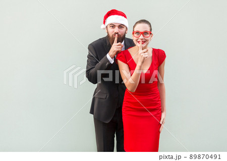 Shh sign. Big secret, shut up! Well dressed businessman and woman looking at camera and showing quiet sign. Studio shot Shh sign. Big secret, shut up! Well dressed businessman and woman looking at camera and showing quiet sign. Studio shot 89870491