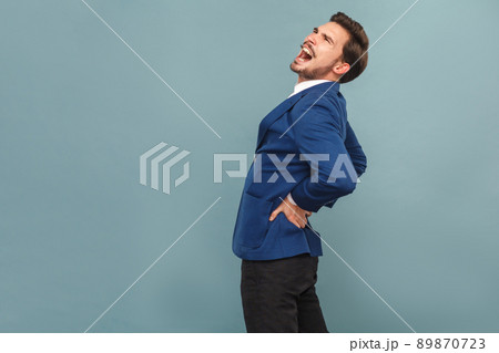 Man have pain in back. Stones or kidneys organs. portrait of handsome bearded businessman in blue suit and white shirt. Indoor studio shot, isolated on light blue background 89870723