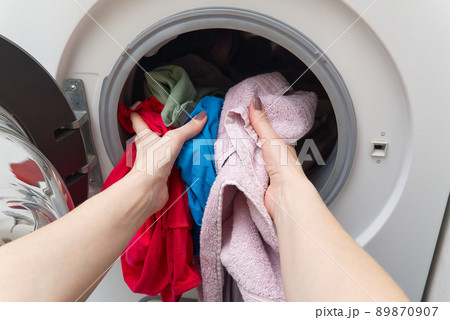 white front-loading washing machine, full of clothes. cleaning laundry. dirty laundry in the washing machine. white front-loading washing machine, full of clothes. cleaning laundry. dirty laundry in the washing machine. 89870907