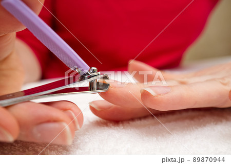 Woman Clipping Nail s with Forceps. Female cuts his nails on a white background with tweezers for nails. manicure procedures yourself at home 89870944
