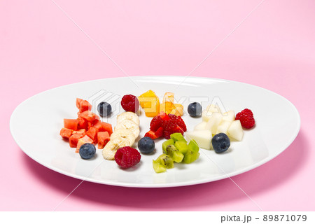 Fresh fruit salad on white plate. Mixed fruit in white plate healthy food style. Useful fruit salad of fresh fruits and berries on pink background 89871079