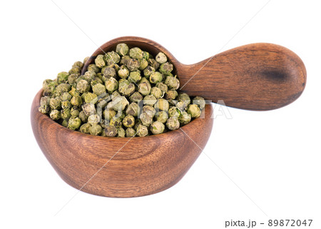 Green peppercorns in wooden bowl and spoon, isolated on white background. Organic spice. Dry green pepper grain. 89872047