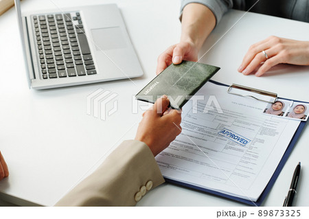 Horizontal high angle of Muslim woman giving her passport to consular officer to make travel visa after getting application approval Horizontal high angle of Muslim woman giving her passport to consular officer to make travel visa after getting application approval 89873325
