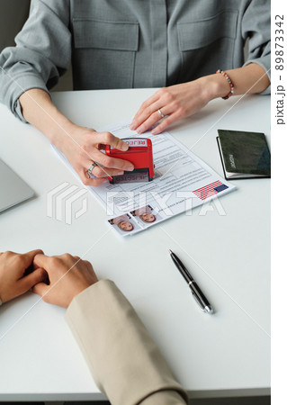 Vertical high angle view in unrecognizable US embassy worker putting rejected stamp on visa application after interview Vertical high angle view in unrecognizable US embassy worker putting rejected stamp on visa application after interview 89873342