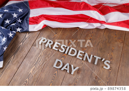 words presitdents day laid with silver letters on wooden surface near US flag words presitdents day laid with silver letters on wooden surface near US flag 89874358