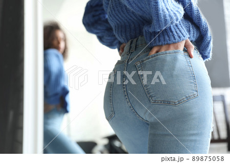 Woman wearing jeans near mirror indoors, closeup Woman wearing jeans near mirror indoors, closeup 89875058