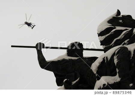 Helicopter in the sky over the monument to George the victorious, covered with snow, in Moscow. 89875346