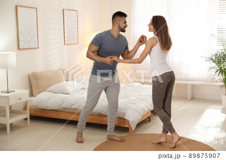 Lovely young couple dancing in bedroom at home Lovely young couple dancing in bedroom at home 89875907